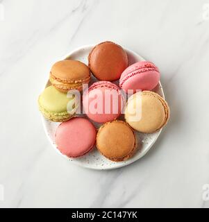 plate of various colorful macaroons on marble table, top view Stock Photo