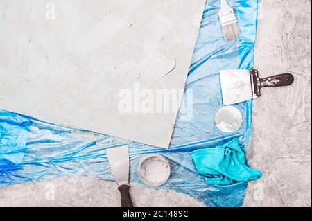 plastered Board, metal spatula, jar of cement, brush for molar paint, blue rag and a blue celophane floor covering. self-repair and home decor, buildi Stock Photo