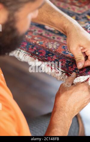 traditional hand sewing fixing old vintage antique persian carpet up close Stock Photo