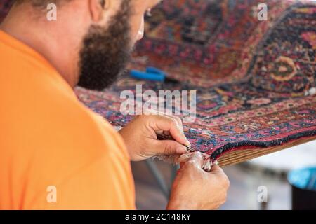 traditional hand sewing fixing old vintage antique persian carpet up close Stock Photo