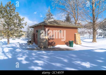 Storage shed with hip roof and brown wooden wall against snow and cloudy sky Stock Photo