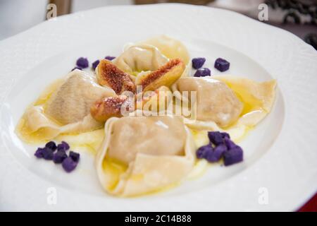 Ravioli with ricotta cheese, figs and purple sweet potatoes, served in a white plate, Italy Stock Photo