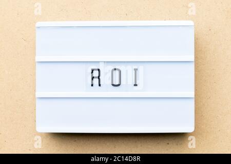 White lightbox with word ROI (Abbbreviation of Return on Investment) on wood background Stock Photo