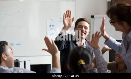 Happy diverse employees giving high five together celebrating shared ...
