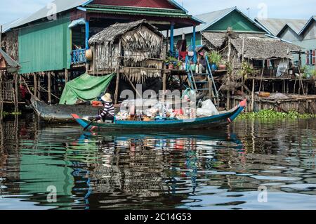 Kampong Phluk, Cambodia - December 4, 2011:  A woman paddling a heavily laden wooden boat through the floating village of Kampong Phluk on the Tonlie Stock Photo