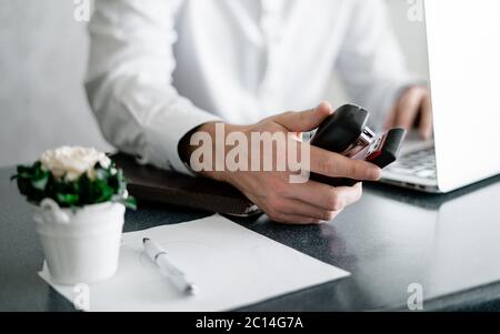 Businessman in home office holding stapler and documents isolated on white background. Professional using laptop and smart phone in the office Stock Photo
