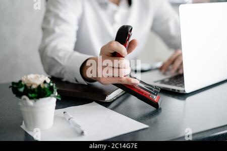 Businessman in home office holding stapler and documents isolated on white background. Professional using laptop and smart phone in the office Stock Photo