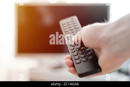 Hand holding use remote control and watching TV in house with warm and relaxing atmosphere. Home concept Stock Photo