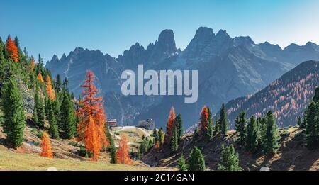 Panoramic view of magical Dolomite peaks at the national park Three Peaks (Tre Cime, Drei Zinnen) and mountain hut in Autumn colors during sunset back Stock Photo