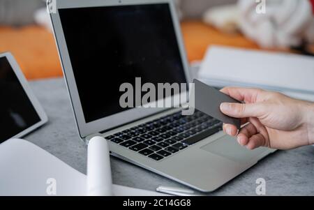 Home office, remotely working concept. Close up of male hands typing on computer keyboard.  Workplace - laptop, tablet pc, smart phone and cup of tea. Stock Photo