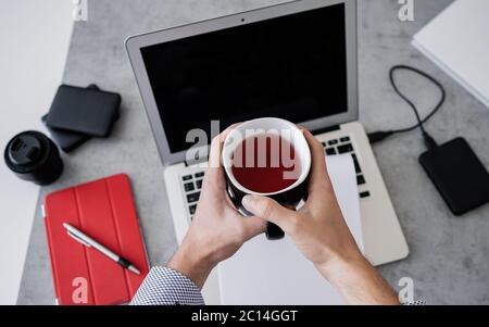 Top view of man is working remotely at home, workplace - laptop, tablet pc, smart phone and cup of tea. Home office Stock Photo