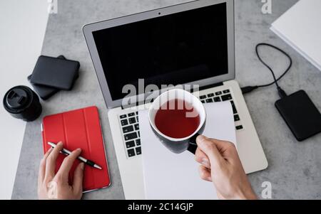 Top view of man is working remotely at home, workplace - laptop, tablet pc, smart phone and cup of tea. Home office Stock Photo