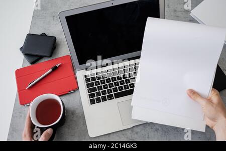 Top view of man is working remotely at home, workplace - laptop, tablet pc, smart phone and cup of tea. Home office Stock Photo