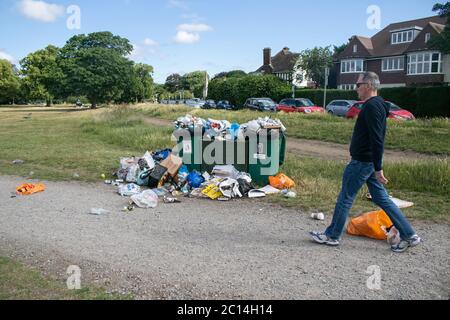 WIMBLEDON LONDON, UK. 14 June 2020. Garbage bins are overfilled with  many rubbish  items on Wimbledon Common including plastic bags, empty pizza boxes, beer bottles and cans left behind as people take advantage of warm weather outdoors  during the easing of the coronavirus lockdown. Credit: amer ghazzal/Alamy Live News Stock Photo