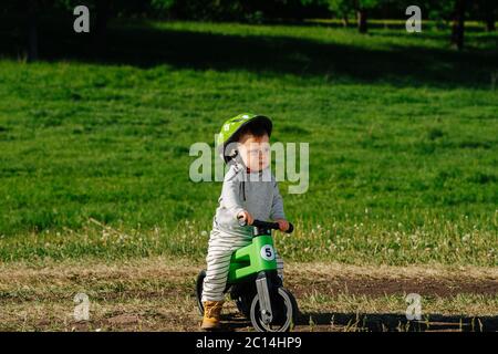 Grumpy little kid foot riding on a three-wheel bike Stock Photo