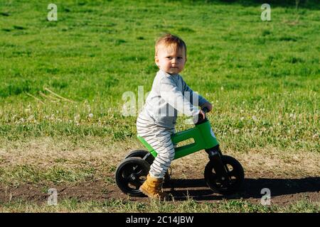 Grumpy little kid on a three-wheel bike. He's looking at camera. Stock Photo