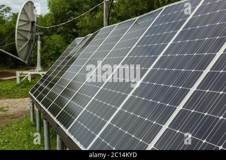 Solar panels and satellite dish for energy and communication in suburbs. Stock Photo