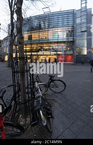 View of the department store 'De Bijenkorf' from the Maastrichter Brugstraat at the start of the evening with illuminated shop windows in Maastricht Stock Photo