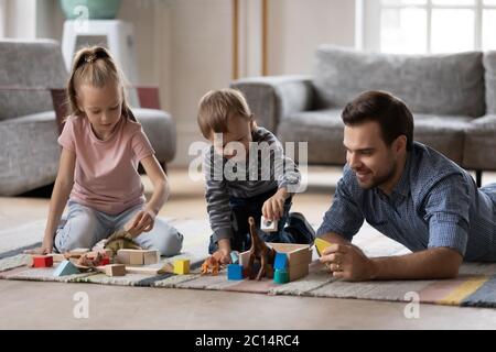 Father with adorable kids playing with toys on warm floor