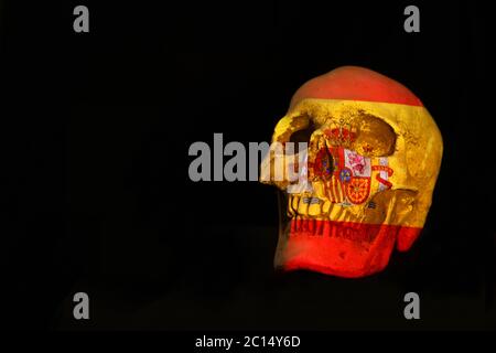 Spanish national flag projected over an isolated skull set against a plain black background Stock Photo