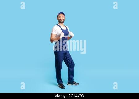 Full length self-confident professional handyman in overalls pointing himself and looking with arrogance, proud of job in service industry, house repa Stock Photo
