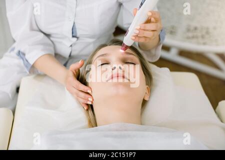 Cropped shot of pretty woman getting birthmark or vascular net removed by laser at beauty salon. Professional dermatologist using laser removing moles Stock Photo