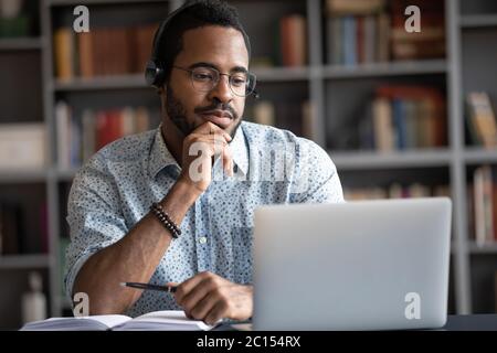 African guy wearing headset learn foreign language using internet websites Stock Photo