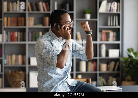 African man talking by cellphone received great news feels happy Stock Photo