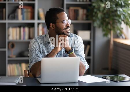 African male employee looking at window taking break from work Stock Photo