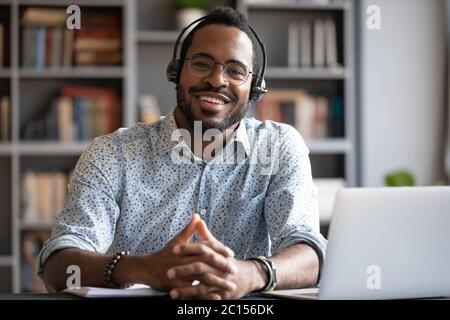 African man wear headset sit at desk looking at camera Stock Photo