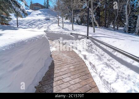 Stone brick pathway with metal handrails amid deep layer of snow in winter Stock Photo