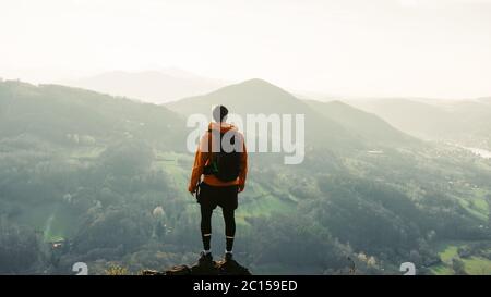 Hiker watching to Sun at horizon. Beautiful moment the miracle of nature. Colorful mist in valley. Man hike. Mountain Pass Stock Photo