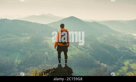 Hiker watching to Sun at horizon. Beautiful moment the miracle of nature. Colorful mist in valley. Man hike. Mountain Pass Stock Photo