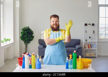 Cleaning man in room. Cheerful man in rubber gloves with cleaning products at home Stock Photo