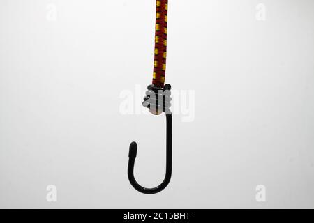 Close up of isolated black metal hook with elastic rope, white background (focus on center) Stock Photo