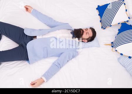 One more long day ended. Feel tired and sleepy. Sleepy guy in formal clothes sleep on bed. Lack of sleep. Need more sleep. Evening time. Businessman exhausted. Drained physical and mental resources. Stock Photo