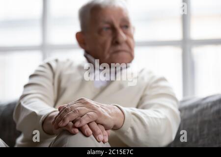 Close up thoughtful older man sitting with folded hands Stock Photo