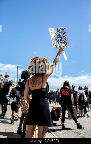 Brighton, UK. 13th June, 2020. A woman holds up a Black Lives Matter placard during the protest in Brighton.Local activists in England organised a protest in the centre of Brighton in solidarity with the BLM protesters in the US to highlight the systemic racism and police brutality in the UK. Credit: SOPA Images Limited/Alamy Live News Stock Photo