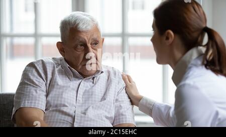 Female doctor comforting upset older patient at meeting Stock Photo