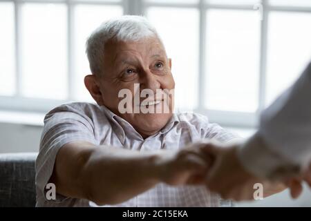 Close up smiling older man holding doctor hands Stock Photo