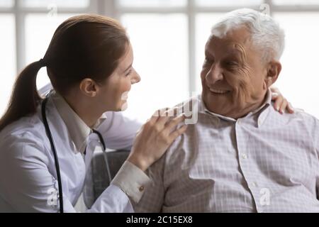 Close up caring female doctor talking to smiling older man Stock Photo