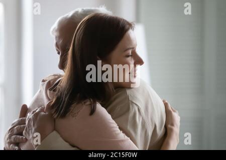 Smiling young woman hugging older man, enjoying tender moment Stock Photo