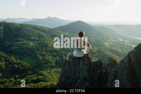 Traveler relax on the edge rock. Nature and adventure composition. Sharp exposed sandstone hills. Leisure activity. Sport tourism. Adventures of hiker Stock Photo