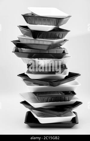 White and black foam food container trays (Styrofoam trays) stacked. Isolated on white background. Close-up. Vertical shot. Stock Photo