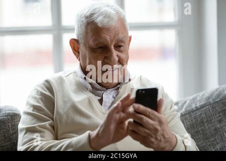 Close up smiling older man using phone, looking at screen Stock Photo
