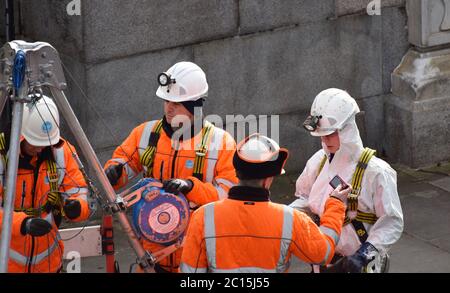 4 Specialist engineers working on something deep in the ground in the centre of London next to the river Thames. 3 men and 1 woman. Stock Photo