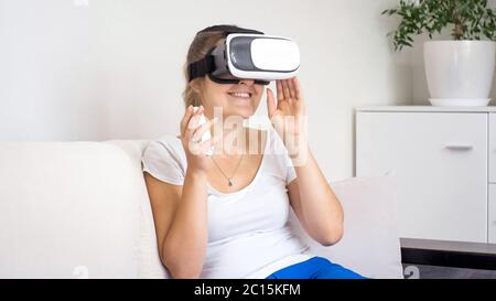 Portrait of young woman enjoying using VR goggles and holding remote control in hand Stock Photo