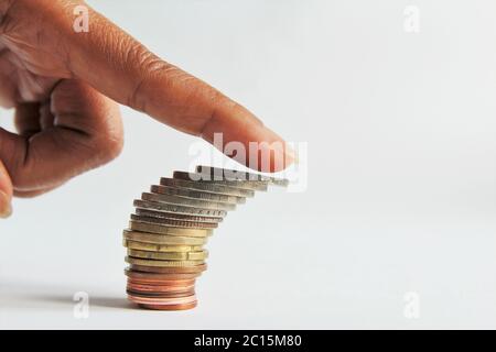 Oppression concept,Close up index finger pushing on top of stack of money coins are about to fall down. photo isolate on white side view copy space Stock Photo