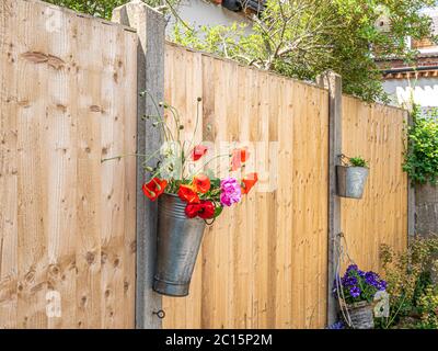 A solid boundary fence between neighbouring properties, with wood panels slotted between concrete posts and flower containers attached. England, UK. Stock Photo