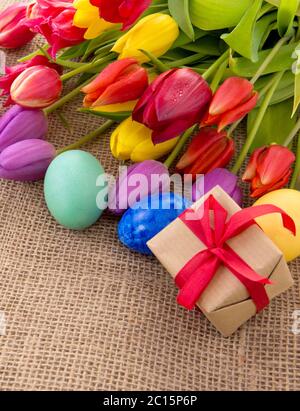 Spring tulips with colorful easter eggs and gift box. Stock Photo